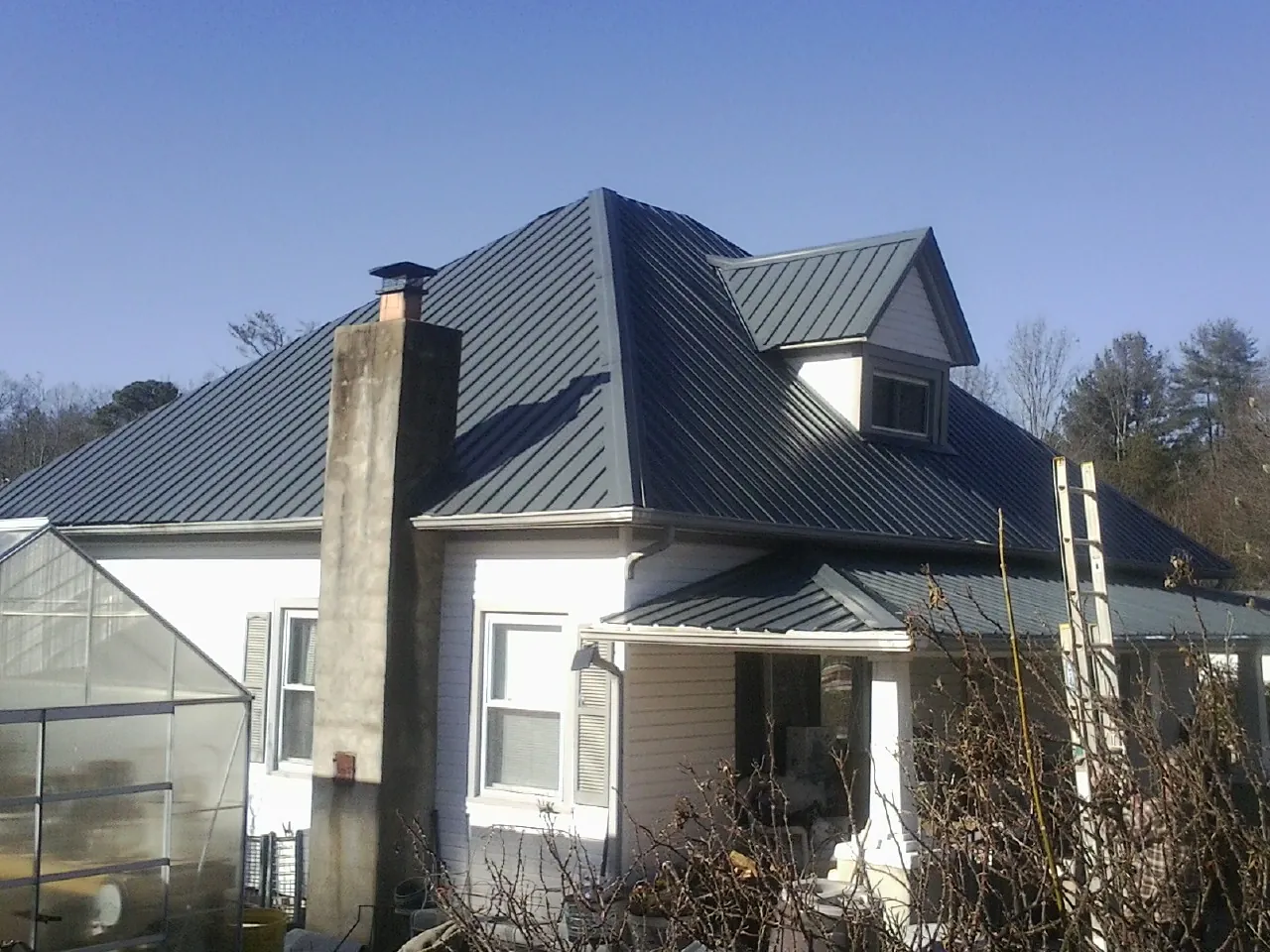Dark blue standing seam metal roof on a white farmhouse with dormer — Slate & Tile Roof Repair by Roofing Brothers in Fort Payne