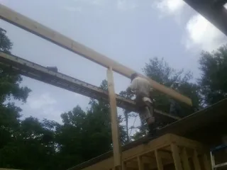 Carpenter setting a ridge beam over a new addition frame — Ice Dam Removal by Roofing Brothers in Fort Payne