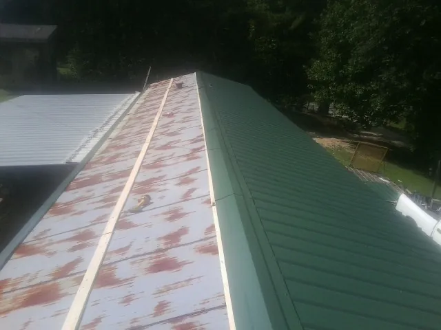 Old rusted panels beside newly installed green metal roofing — Wind Damage Roof Repair by Roofing Brothers in Fort Payne