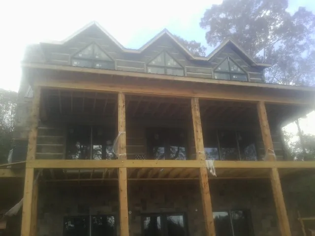 Dormers and porch framing on a large log home under construction — Roof Coating work by our crew in Fort Payne