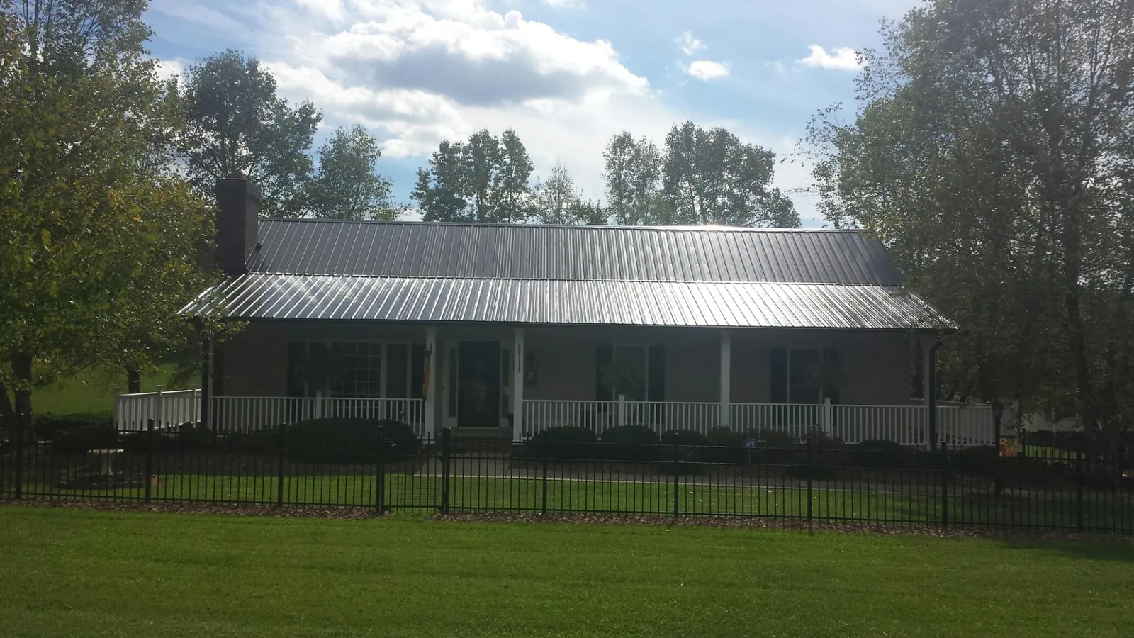 Gray metal roof on a brick ranch with a full width front porch — Gutter Guard Installation work by our crew in Fort Payne