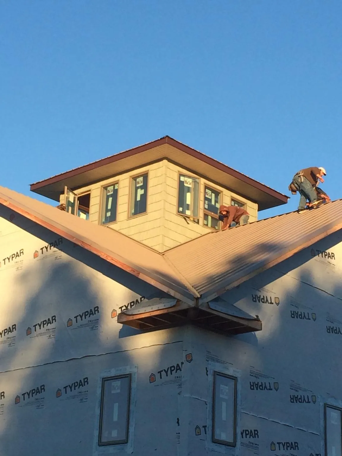 Roofers working around a rooftop cupola on a new metal roof at sunset — Roof Waterproofing in Fort Payne by Roofing Brothers